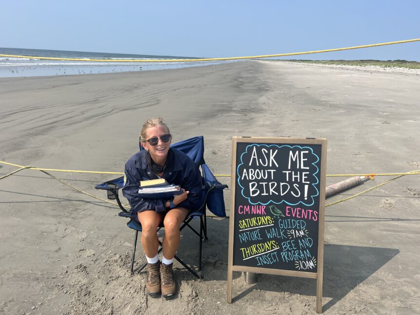 Beach steward next to sign ready to talk to the public.