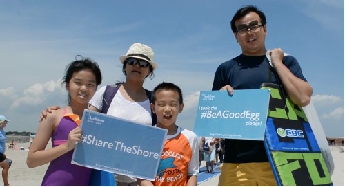 Beachgoers holding Share the Shore signs.
