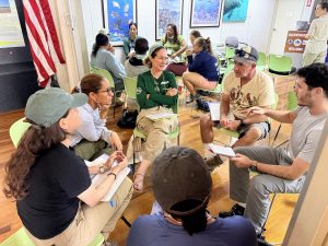 Several people sit in a circle at workshop.