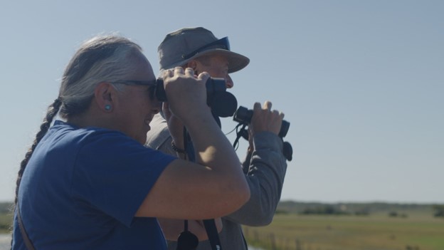 Cree leaders holding binoculars looking at birds.